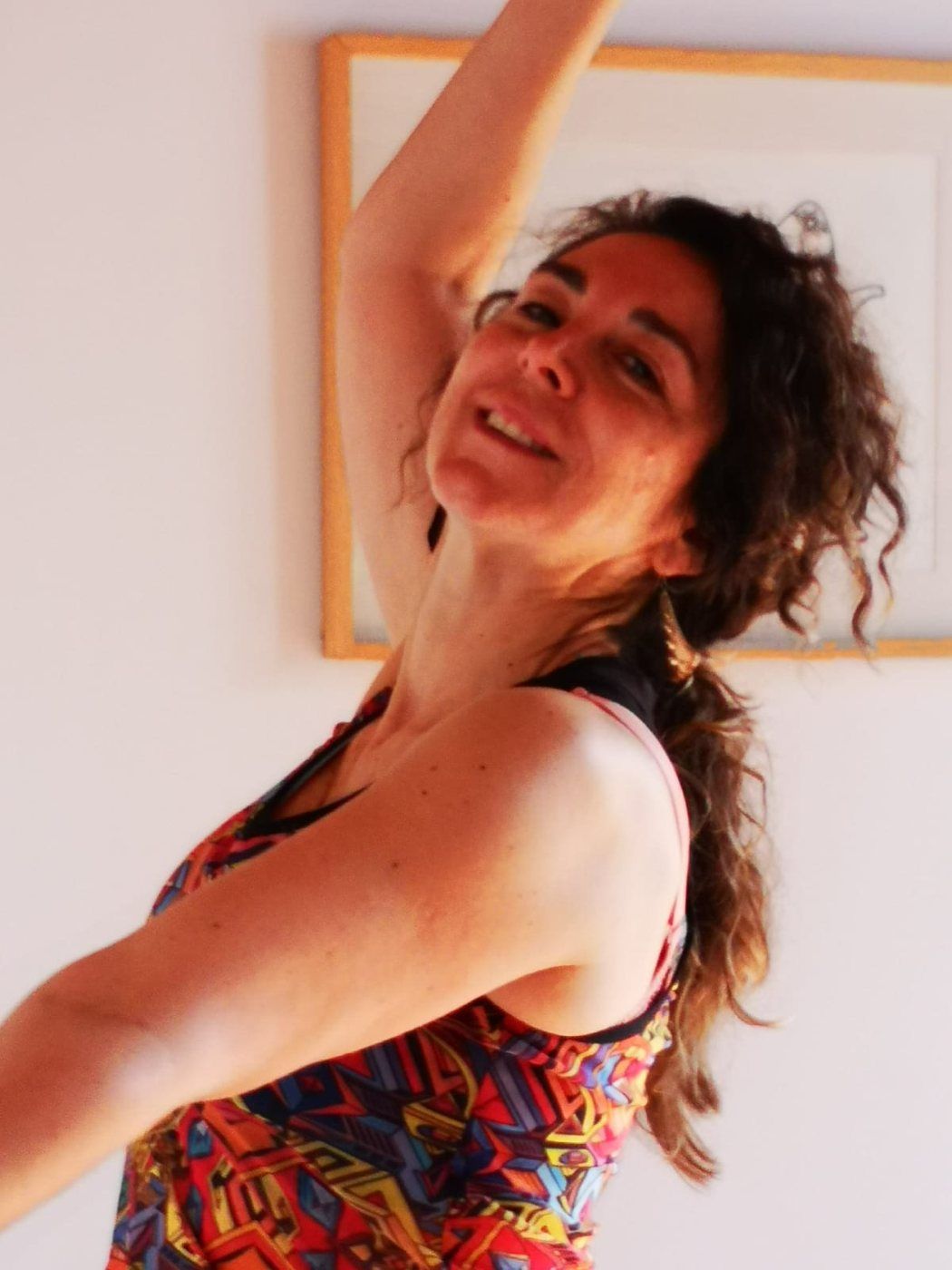 Participante sonriendo mientras danza con el brazo en alto