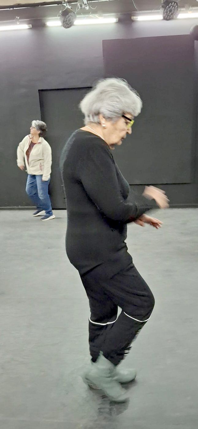 Participante mayor danzando en la sala de teatro
